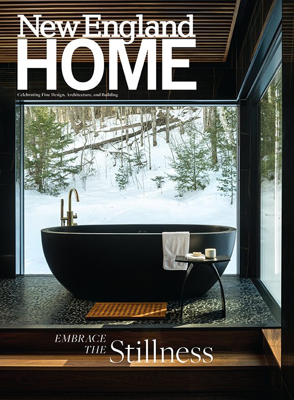 The cover of the January February issue of New England Home featuring a large black bathtub with a view outdoors