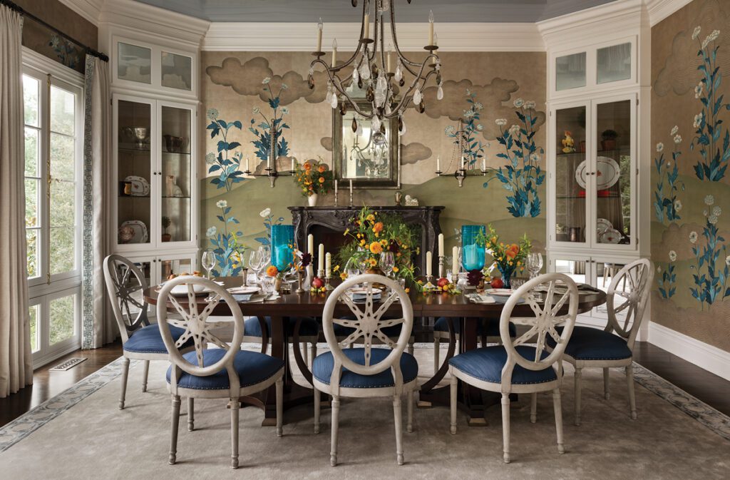 Formal dining room with colorful Gracie wallpaper, dark wood table, and white chairs.