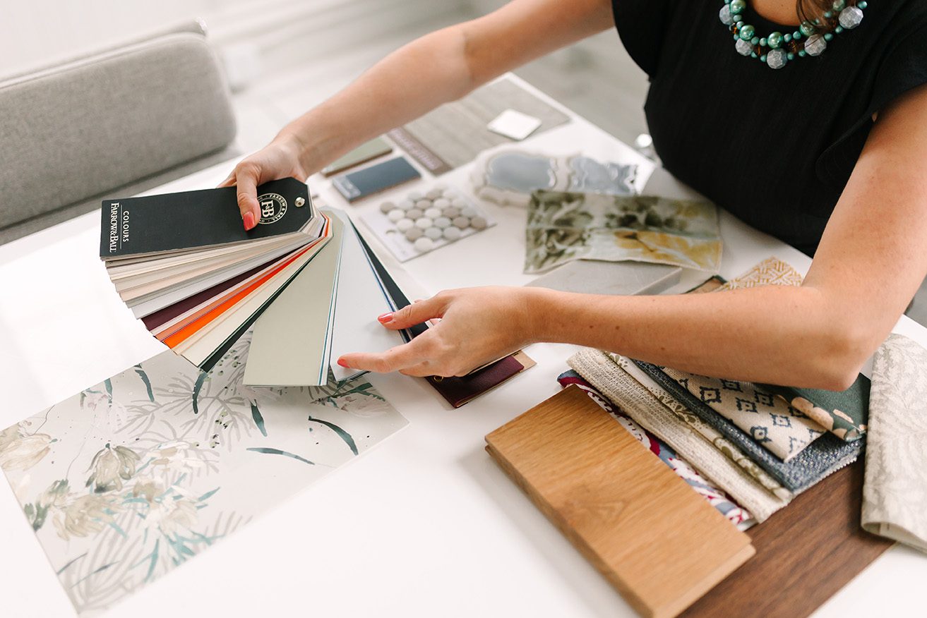Interior designer reviewing color swatches and fabric samples for home décor project on white table