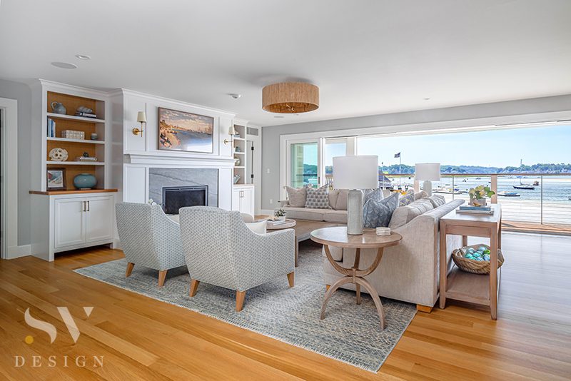 Coastal living room with fireplace and sliding doors to waterfront deck
