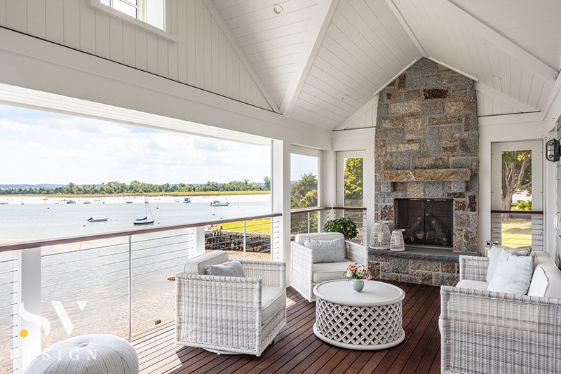 Covered porch with stone fireplace overlooking the water