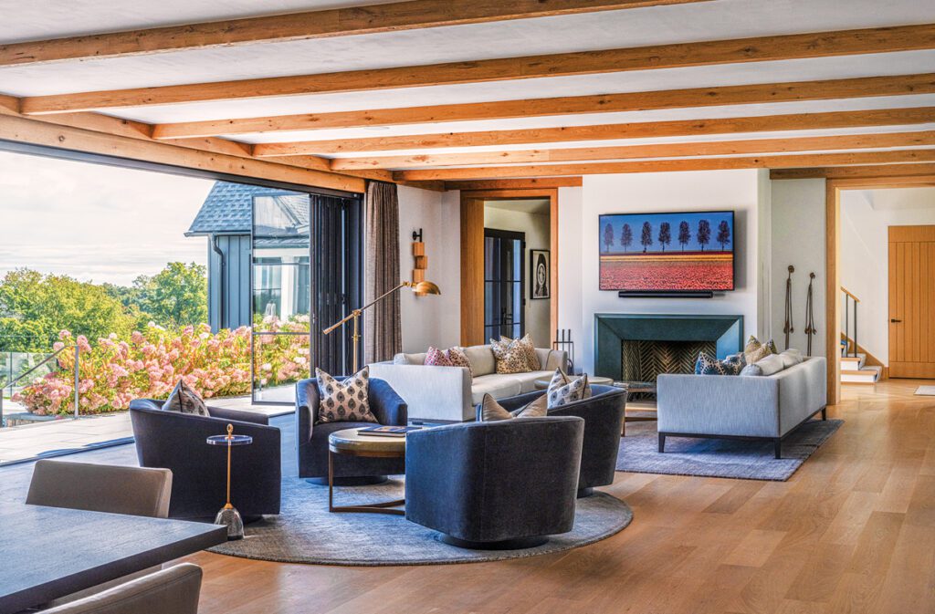 Open-concept great room with exposed wood beams, modern fireplace, and large sliding glass doors.