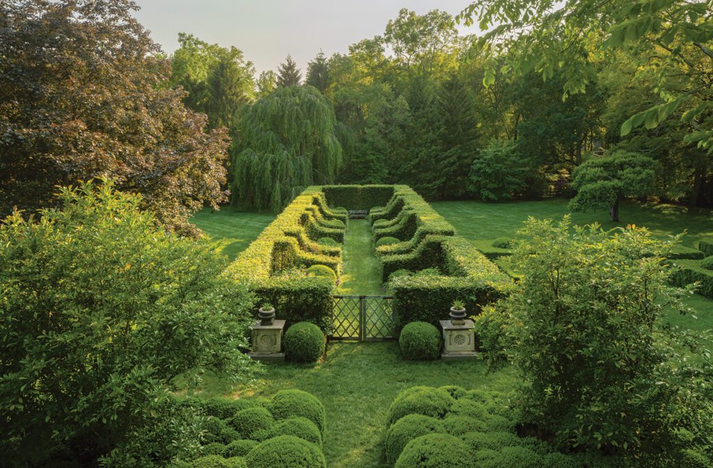Formal garden with manicured boxwood hedges, terraced lawn, and symmetrical landscape design.